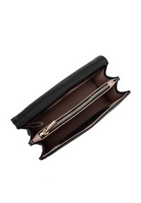 Portafoglio nero con esterno testurizzato, pattina superiore e un compartimento con zip all'interno, caratterizzato da una fodera marrone e dettagli in metallo della zip.