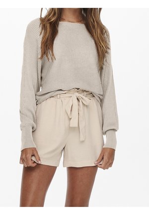 Helle beige, übergroße, gerippte Sweater mit weiten Ärmeln, kombiniert mit beigen hoch taillierten Shorts, die über ein gebundenes Gürtel-Detail verfügen. Glatte Textur.