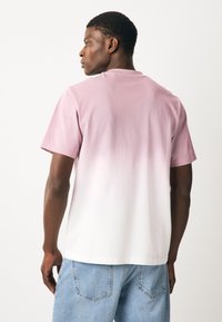 Meeste puuvillane T-särk, millel on üleminek helepunasest valgeni. Lühikesed varrukad, ümarsääreline kaelus, lõdvestunud istuvus ja sile tekstuur.