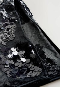 Sort netstof med tætte klynger af sorte og sølvfarvede runde pailletter syet i blomsteragtige mønstre.