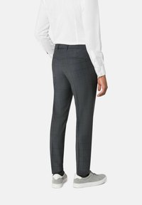 Grijze geblokte broek van stof met een gladde textuur. Slim fit ontwerp met achterzakken. Gepaard met lichtgrijze sneakers.