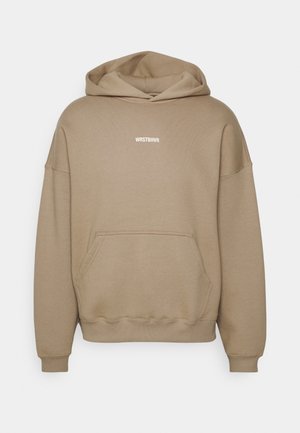 Beiger Kapuzenpullover mit einer Vorderentasche, gerippten Bündchen und einem weißen "WRSTBHVR"-Logo. Weicher Stoff und Design mit entspanntem Schnitt.