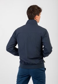 Giubbotto imbottito blu navy con collo alto, polsini elasticizzati e vita aderente. Texture liscia, design minimalista senza loghi visibili.