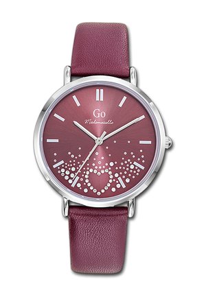 Montre pour femmes avec bracelet en cuir marron foncé, cadran marron foncé, index argentés et un motif de cœur orné de pierres précieuses au-dessus de 6 heures.