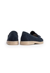 Námořnické semišové slip-on boty s hladkou tan gumovou podešví, kulatou špičkou a dekorativními detaily na přední části, viditelná struktura.