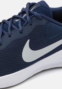Tumed sinine spordijalgpadi, millel on võrgust pealispind, kummist tald ja valge Nike logo. Omab kinnitussüsteemi, et tagada turvaline istuvus.