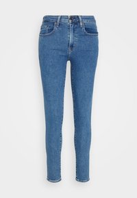 Jeans ajustados de denim azul con una cintura de subida media, diseño de cinco bolsillos y acentos desgastados. Presentan un cierre de botón y un desgaste mínimo.