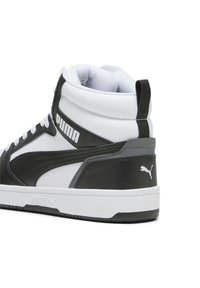Baskets montantes, dessus en cuir noir et blanc, détails texturés, lacets blancs et logo Puma sur le côté et le talon. Semelle lisse.