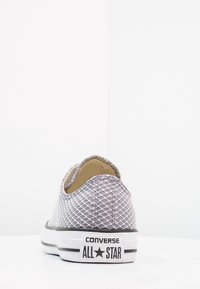 Chaussure à enfiler en maille grise avec un motif texturé, semelle en caoutchouc blanche et accents noirs. Affiche le logo "CONVERSE ALL STAR" sur le talon.
