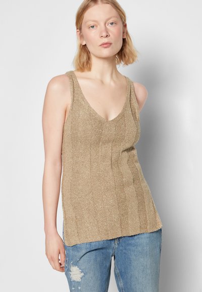 Top de malha bege com decote em V, textura canelada e alças largas, combinado com jeans azuis rasgados.