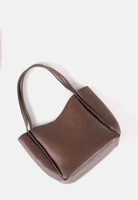 Braune Leder-Tote mit glatter Textur, abgerundeter Form und zwei Schulterriemen. Verfügt über dezente Markenkennzeichnung auf der Vorderseite.