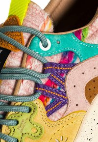 Sneaker multicolore con tomaia in feltro, sovrapposizioni vivaci, diverse trame, dettagli in verde, rosa e blu, con cuciture uniche.