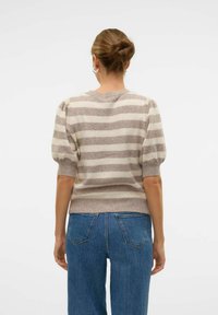 Pull rayé beige et gris clair, avec manches courtes bouffantes, encolure ronde et poignets côtelés, assorti à un jean en denim taille haute.