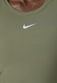 Zielona sportowa koszulka bez rękawów z okrągłym dekoltem, wykonana z gładkiego materiału, z białym logo Nike na piersi.