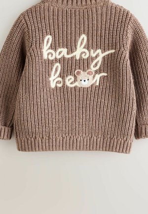 Rudas megztinis su grublėta struktūra. Nugaroje siuvinėtas užrašas „baby bear“ kreminės spalvos ir lokio veido iliustracija.