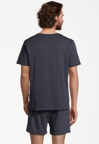T-shirt in cotone blu navy a maniche corte abbinato a pantaloni corti coordinati, caratterizzato da una vestibilità rilassata e una texture morbida con un design semplice.