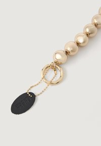 Gold-toned bead necklace with a smooth finish. Features circular metal rings and a black leather tag with the text "FURLA."