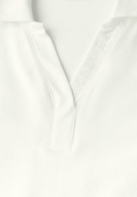 Hvid polo skjorte med struktureret stof, delvis krave og præget "DISCOVER" detaljer nær halsudskæringen. Minimalistisk design.
