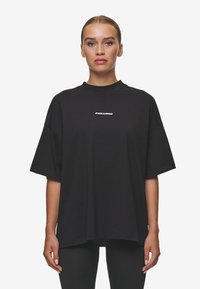 Tricou oversized negru, din bumbac, cu guler rotund și mâneci scurte. Logo-ul "PEGADOR" imprimat în alb în centrul frontal.