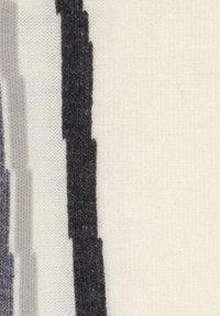 Schwarz-weiße Stoffstreifen mit strukturierten Mustern, die vertikal vor einem hellbeigen Hintergrund verlaufen.