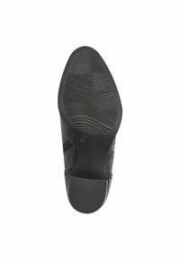Suela de goma negra con surcos texturizados, punta redondeada y acentos de cuero suave. Incluye una cremallera lateral para facilitar su uso.