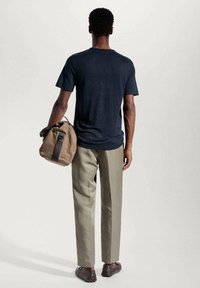 Granatowa koszulka z krótkim rękawem, jasnobeżowe spodnie, brązowa torba z ciemnym paskiem, jednolity kolor, dopasowany krój, teksturowany materiał, noszona nieformalnie.
