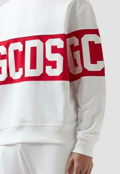 Vit sweatshirt med en röd horisontell rand över bröstet och ärmarna, med stora vita bokstäver "GCOS" på bröstet och "GC" på ärmen.