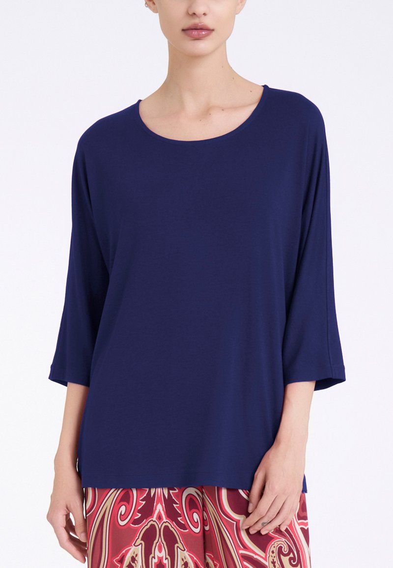 Top blu navy a maniche lunghe con scollatura rotonda. Tessuto morbido con vestibilità comoda, abbinato a pantaloni rossi con motivo.