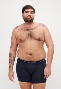 Marineblaue Boxershorts mit schwarzem Bund, der den Text "JACK & JONES" trägt. Weicher, dehnbarer Stoff mit minimalen Nähten.