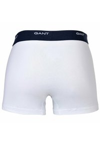 Pantaloni boxers bianchi in cotone con una cintura elastica blu navy con il testo del logo "GANT". Il tessuto ha una superficie liscia e un design aderente.