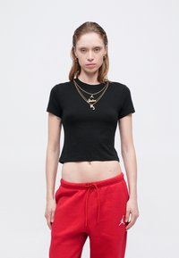 Czarny krótki t-shirt z bawełny, z krótkimi rękawami i okrągłym dekoltem, zestawiony z czerwonymi dresami z logo na lewym udzie.