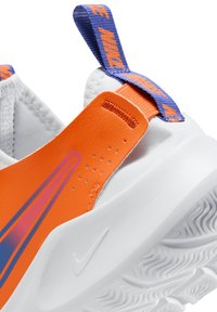 Sneaker orange et blanc avec une semelle texturée, des accents violets sur le patch du talon et le logo, présentant une tige lisse et des détails perforés.
