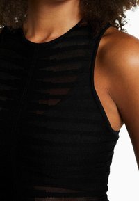 Top nero senza maniche con un design a strati caratterizzato da strisce orizzontali, realizzato in un materiale a maglia testurizzato, che mette in risalto una silhouette aderente.