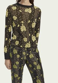 Suéter de punto negro con flores amarillas y acentos verdes. Mangas largas y un cuello redondo, combinado con pantalones a juego con estampado floral.