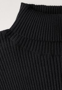 Maglione nero a collo alto con coste, caratterizzato da un motivo a costine verticali e un punto lavorato testurizzato. La vista ravvicinata enfatizza i dettagli del tessuto.