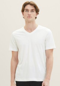 Weißes V-Ausschnitt-T-Shirt aus weichem Stoff, kurze Ärmel mit aufgerollten Bündchen und ein dezentes Logo auf der unteren rechten Seite.