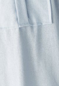 Tessuto intrecciato di colore azzurro chiaro con cuciture visibili e dettagli di cuciture piegate, che mostrano texture e ombreggiature sottili.