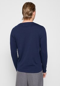 Marineblaues Langarmshirt aus Baumwollmischung mit Rundhalsausschnitt und minimalistischem Design. Glatte Textur ohne sichtbare Muster oder Akzente.