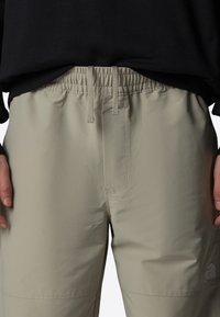 Beige sportbyxor med elastisk midja och dragsko. Slät fram med logotypdetalj på nedre högra sidan. Slät textur.