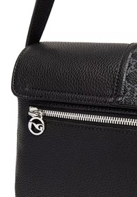 Czarna skórzana torebka o fakturowanej powierzchni, z zamykanym na suwak przegródkiem i charakterystycznym logo na zawieszce zamka.