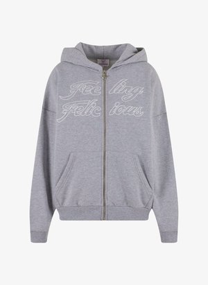 Pelēks kapucis ar rāvējslēdzēju, izgatavots no mīkstas kokvilnas. Iezīmēts ar oderētu kapuci, diviem sānu kabatām un baltu izšūtu tekstu "Feeling Felicious" priekšpusē.