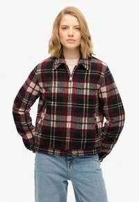 Kurtka flanelowa w kratę w kolorach bordowego, czarnego i kremowego. Posiada zamek z przodu, kołnierz oraz dwie boczne kieszenie. Miękka tekstura i dopasowany krój.