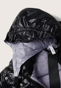 Veste noire brillante à capuche avec doublure intérieure grise et détails visibles de fermeture éclair et boutons-pression.