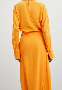 Langärmliges Kleid in lebhaftem Orange, mit tiefem Rückenausschnitt, glattem Stoff und enganliegenden Manschetten mit Knopfdetail.