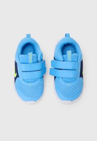 Baskets de sport bleues avec une tige en mesh et synthétique, dotées de deux brides Velcro, d'accents contrastants en bleu marine et d'une semelle extérieure blanche.
