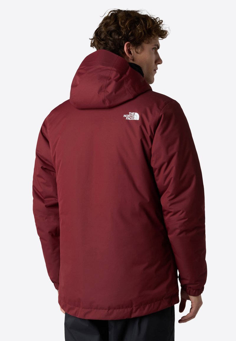 Giacca piumino bordeaux con cappuccio, dotata di polsini elasticizzati e un logo bianco sulla parte superiore della schiena. Tessuto liscio, isolato e con una vestibilità comoda.