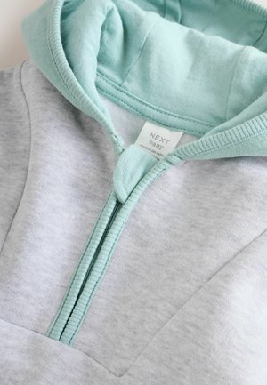 Hanorac gri cu fermoar și căptușeală verde mentă în glugă. Are un buzunar frontal și este din material moale de bumbac. Etichetă cu inscripția "NEXT baby".
