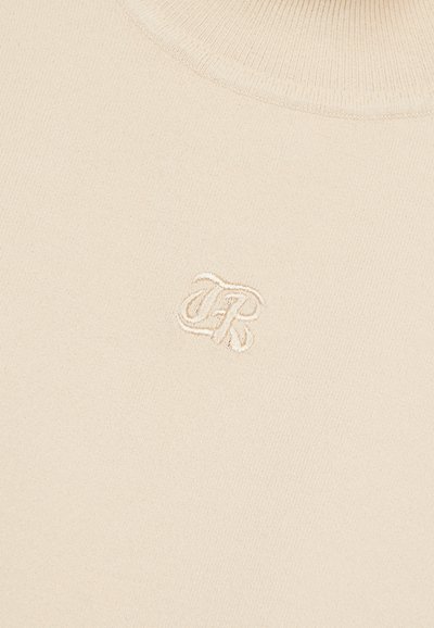 Maglione beige in maglia con collo alto e texture sottile. Presenta un logo ricamato "FR" nell'angolo in basso a sinistra.
