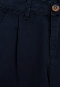 Námornické modré nohavice s plisovaným predným dielom, pútkom na opasok a zapínaním na gombík, vyrobené z ľahkej tkaniny s hladkou textúrou.