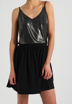 Robe noire avec un haut ajusté métallique gris foncé et une taille élastique. Jupe évasée au-dessus du genou, avec de fines bretelles fines.